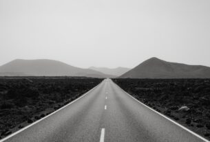 Black and white photo of a road leading to mountains