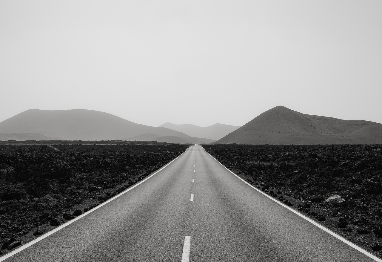 Black and white photo of a road leading to mountains